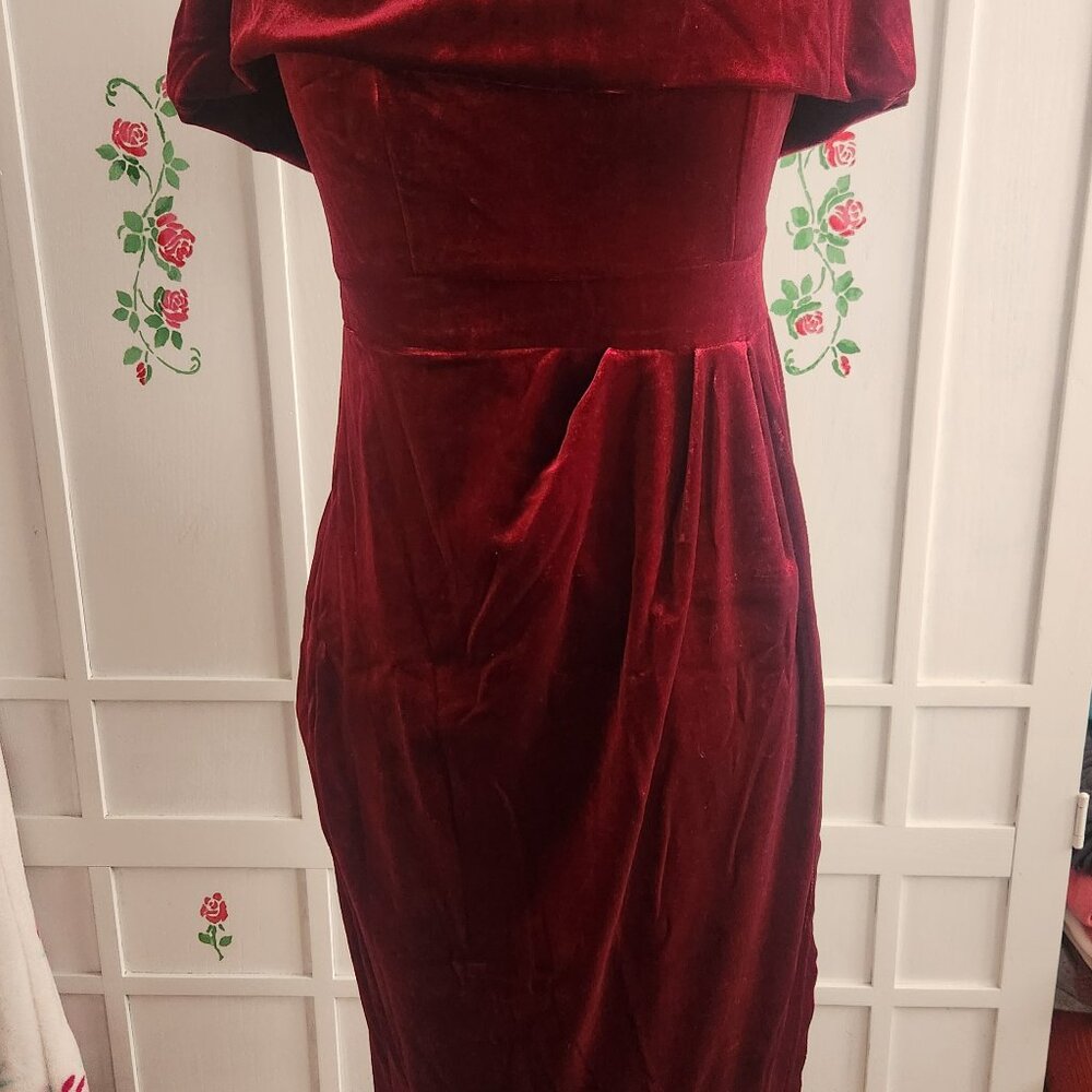 a red velvet dress with a draped or cowl-style neckline and a fitted waist.